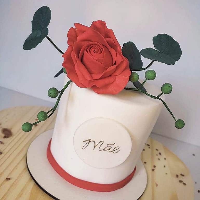 Bolo branco e vermelho com rosa no topo