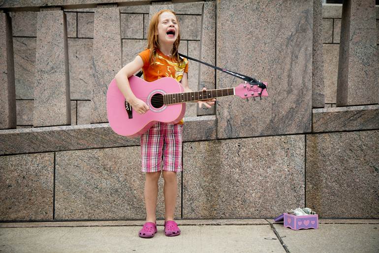 Criança cantando com violão rosa