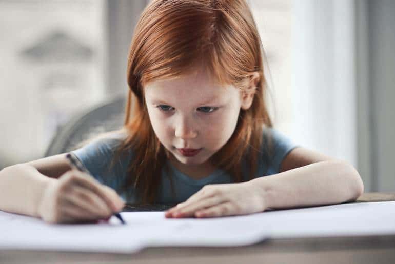 Criança ruiva escrevendo