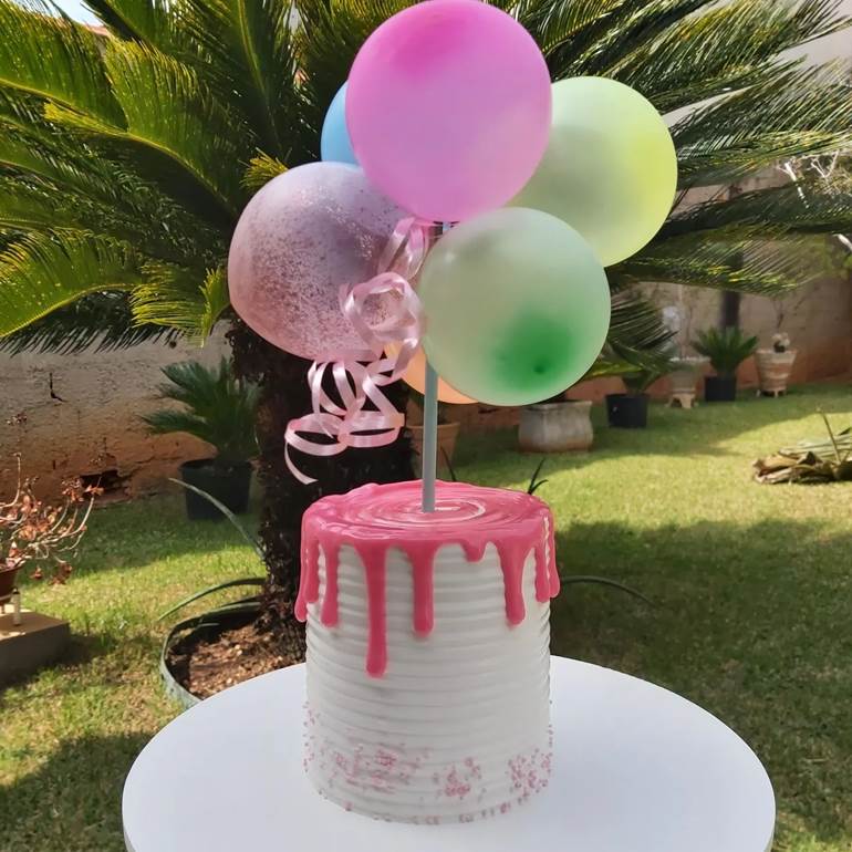 Bolo com balão branco e cobertura rosa