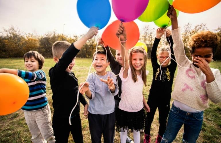 Dinâmica de crianças segurando balões coloridos