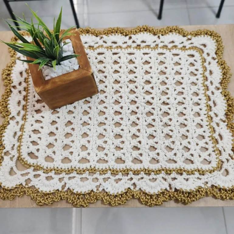 Sousplat de crochê branco e dourado com planta