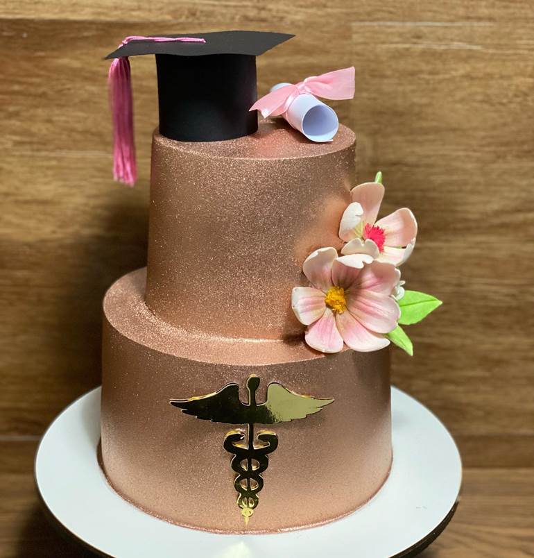 Bolo rosê com glitter capelo, diploma e flores