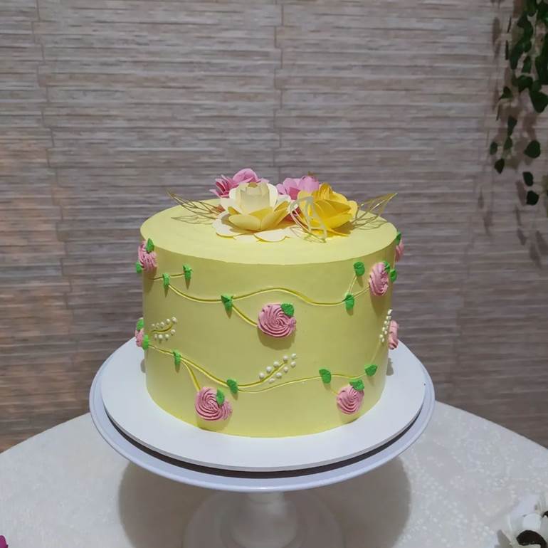 Bolo com flores rosas de chantilly e folhas verdes