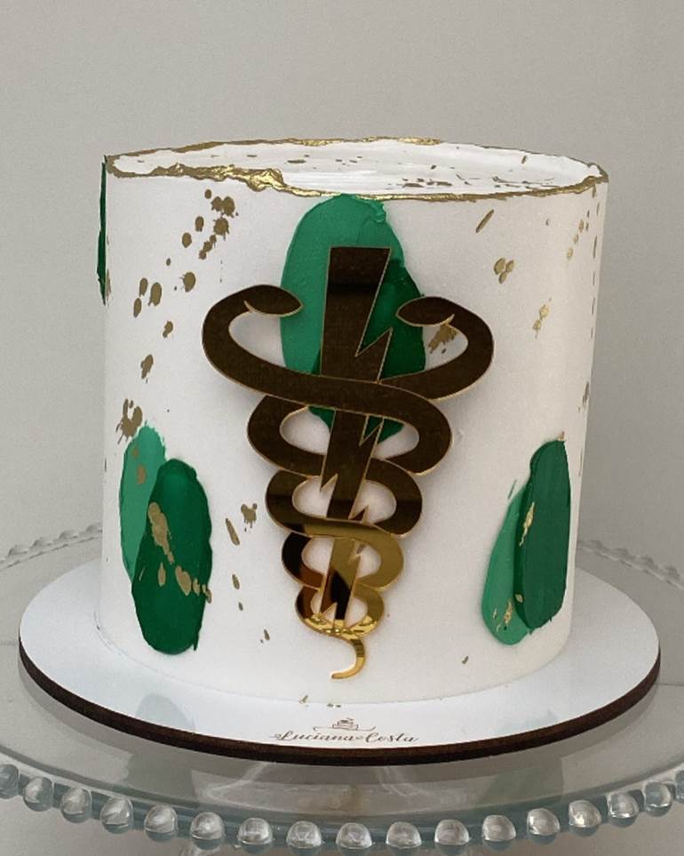 Bolo branco com símbolo dourado e detalhes verdes